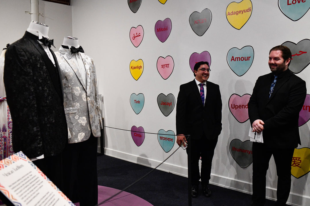 Exhibit visitors view two mens' suits from a gay wedding held in Kentucky.